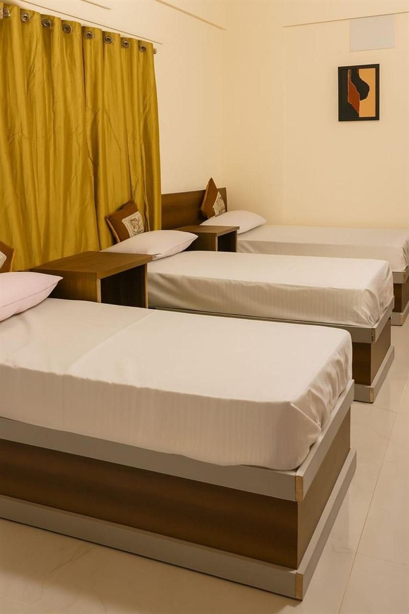 Bright triple room with white bedding and olive-gold curtains