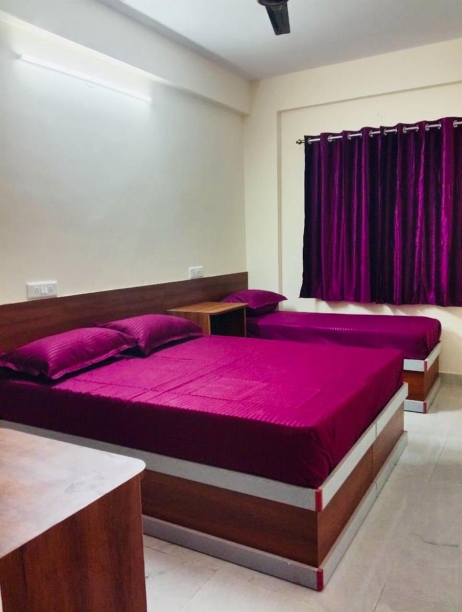 Double room with rich magenta bedding and velvet curtains at AMIGO ladies PG