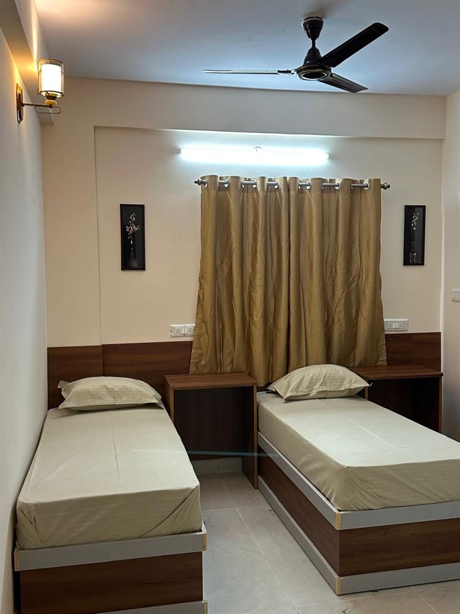 Twin room with gold curtains, wall lamp and study desks