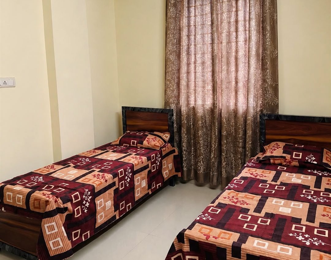 Twin-sharing room at AMIGO Luxury ladies PG, SG Palya — two single beds with wooden headboards and sheer curtains